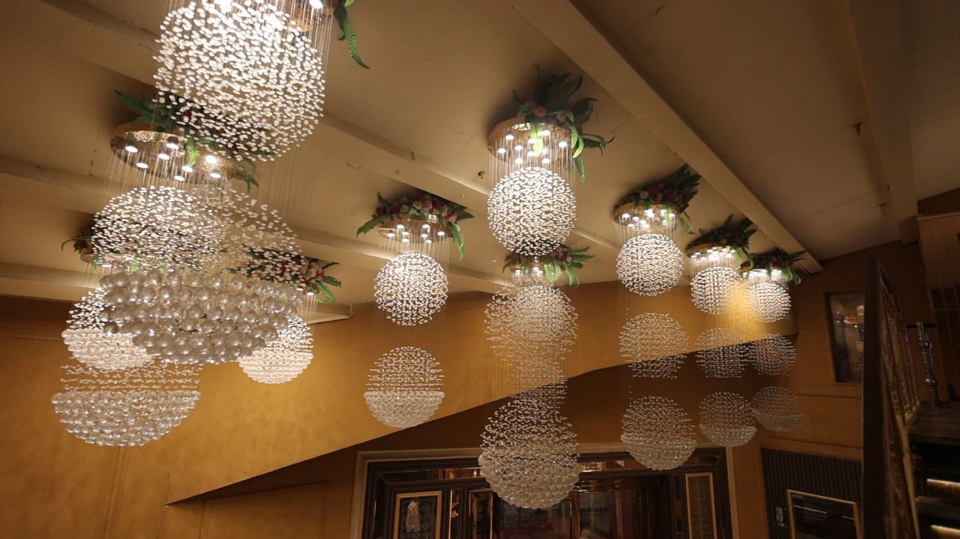Cascading crystal chandelier spheres with floral arrangements at The Great Palace Banquet Hall ceiling decor
