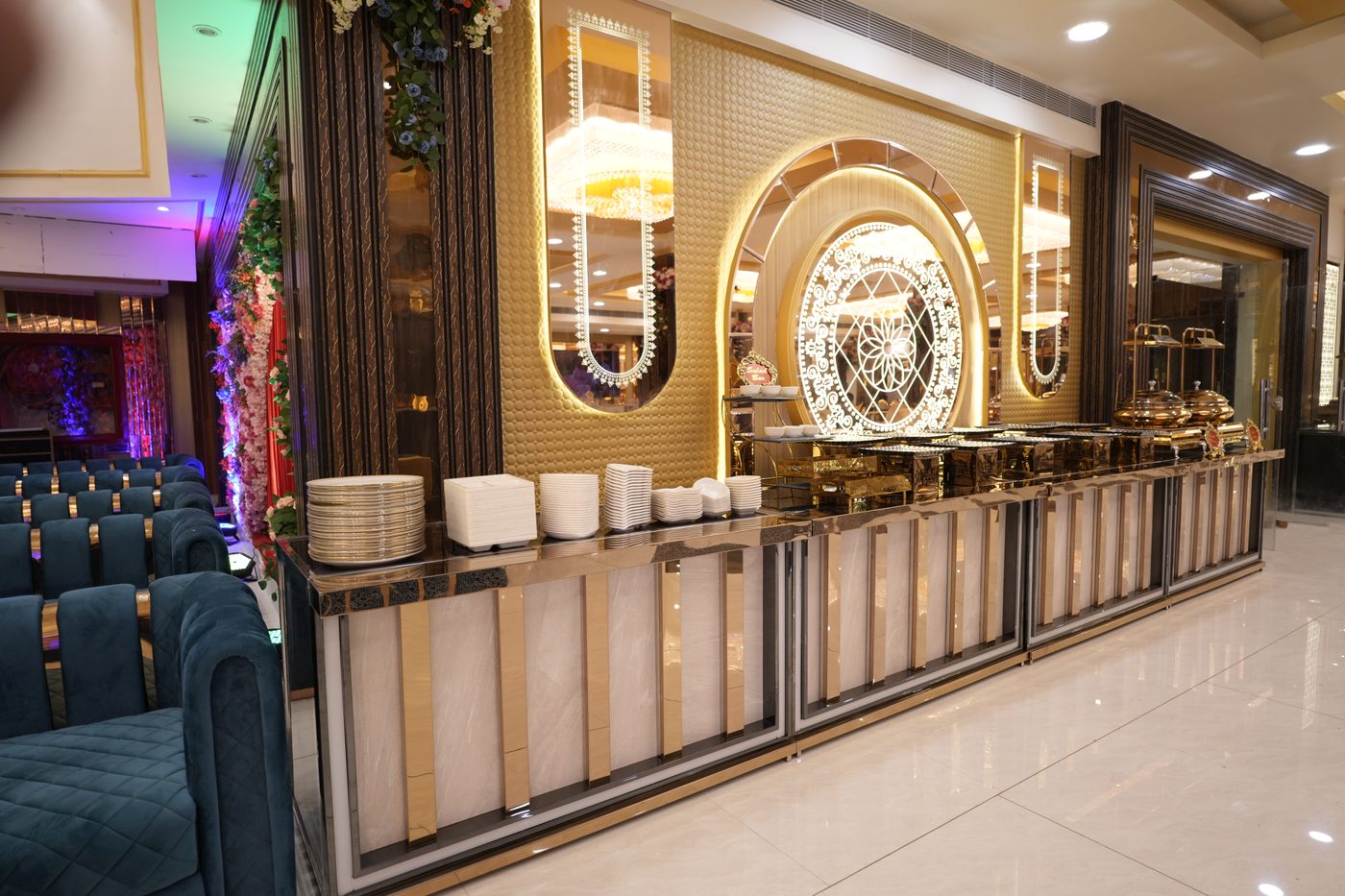 Elegant buffet counter with white china plates and gold rosette backdrop at The Great Palace Banquet Hall