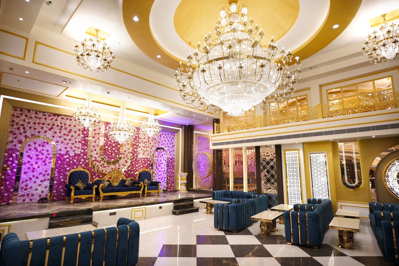 Wide angle view of The Great Palace Banquet Hall with chandelier, stage and gold balcony railings